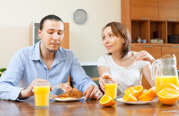 Obraz na płótnie Canvas couple having breakfast with scrambled eggs and oranges
