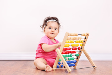 Little girl playing with an abacus seated on floor