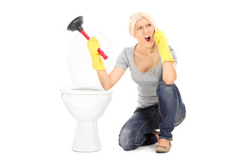 Angry woman holding plunger and talking on phone