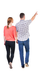 Obraz premium Back view of walking young couple (man and woman) pointing.