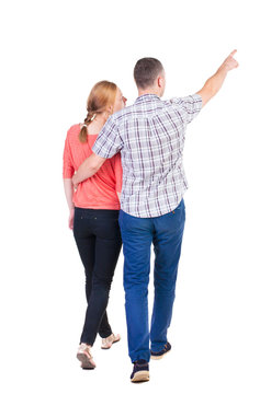 Back view of walking young couple (man and woman) pointing.