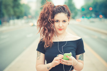 Portrait of young woman listening to music on street