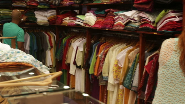 woman chooses clothes in a shop near the shelves