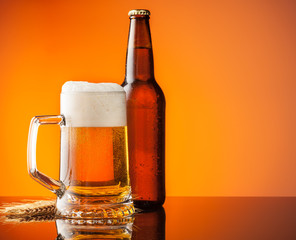 Glass and bottle of beer with orange background