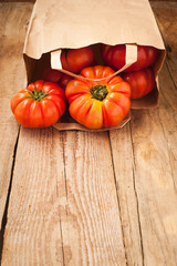 Tomatoes falling out of a paper bag on wooden rustic table