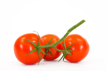 Three fresh tomatoes with green leaves isolated