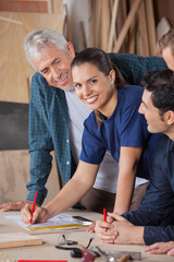 Female Carpenter Working On Blueprint With Colleagues