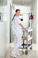 Technician Pushing Medical Cart In Hospital Hallway
