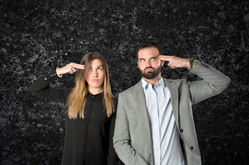 Couple making suicide gesture over black background