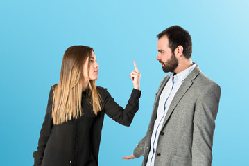 Girl doing the horn sign at her boyfriend over blue background