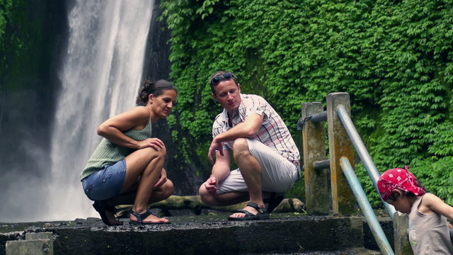 Happy family in front of beautiful waterfall, slow motion shot