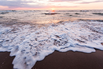 Sea beach at sunset with water splashes