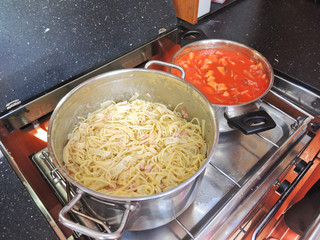 cooking pasta with sausage and meat gravy on stove