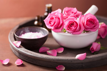 Obraz na płótnie Canvas spa set with rose flowers mortar essential oils salt