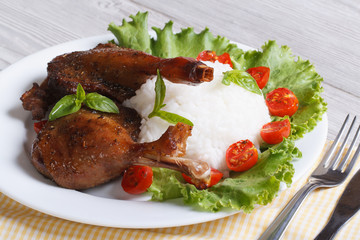 roasted duck leg with rice and salad on the plate horizontal