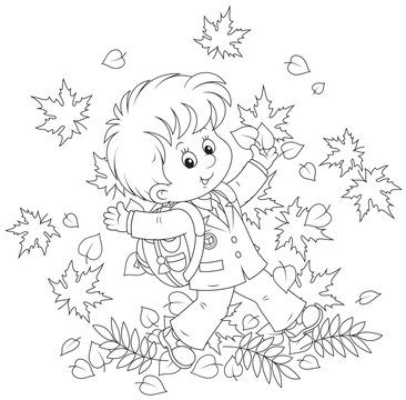 Joyful schoolboy throws up autumnal leaves