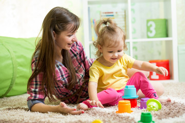 child girl and her mother playing together with toys