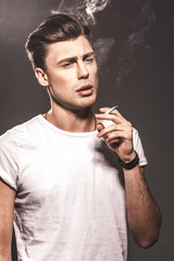 Handsome young man smoking cigarette