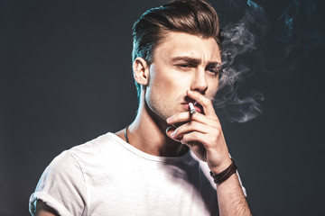 Handsome young man smoking cigarette