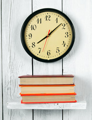 Naklejka premium Watches and books on a wooden shelf.