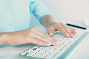 Female hands typing on keyboard, on light background