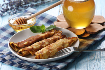 pancakes with honey on a plate, the honey in a glass bowl and la