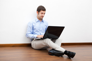 Young man looking thoughtful and using laptop