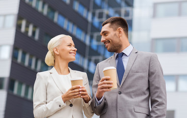 smiling businessmen with paper cups outdoors