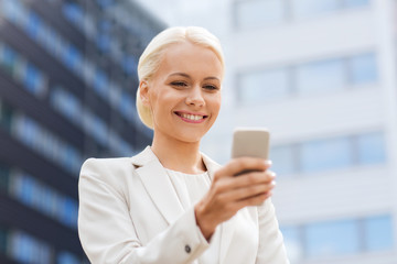 smiling businesswoman with smartphone outdoors
