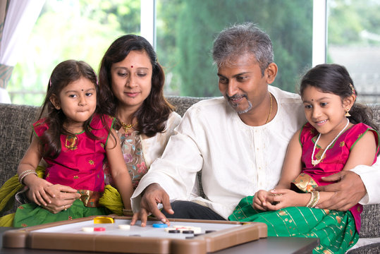  Indian family playing carrom game at home. Parents and children