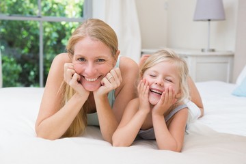 Cute little girl and mother on bed