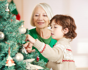 Großmutter und Enkel schmücken Weihnachtsbaum zu Weihnachten