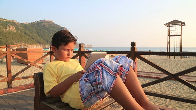 child with digital tablet on the beach