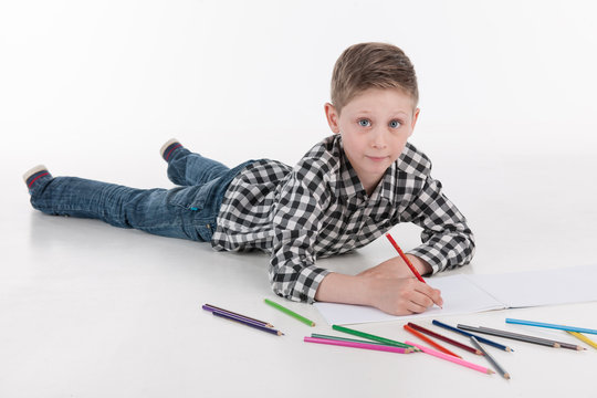 boy lying on floor and drawing pictures.