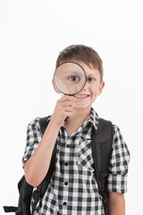 Happy schoolboy wearing backpack and holding magnifying lens.