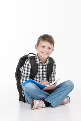Happy schoolboy with notebook isolated on white background.
