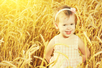 happy little girl in a field of golden wheat in the summer