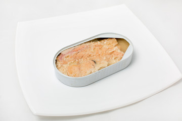 open can of fish in a plate on a white background