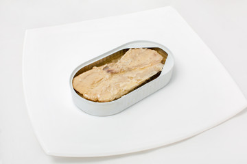 open can of fish in a plate on a white background
