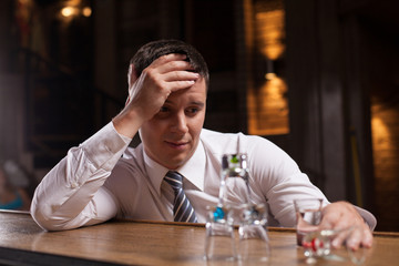 Upset businessman having drink in bar.