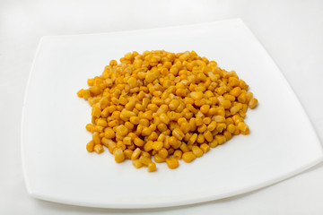 Large grain of corn in a dish on a white background