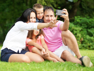 Fototapeta premium family taking selfies with smartphone in park