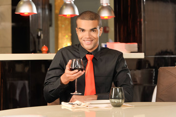 Elegant young man holding glass of red wine.