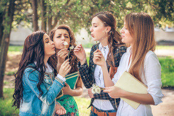 Group of College Girls Blowing Dandelion Seeds