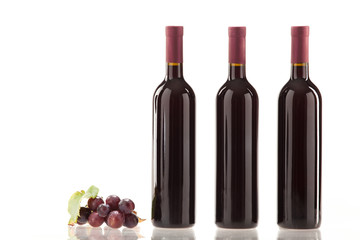 Obraz premium Rotwein im Glas mit Frucht, Blätter und Weinflasche