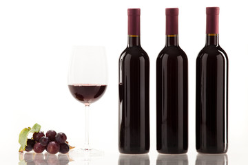 Obraz premium Rotwein im Glas mit Frucht, Blätter und Weinflasche