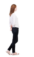 back view of standing young beautiful  blonde woman in jeans.