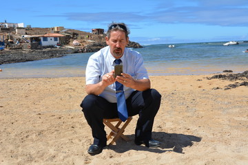 Business man in suit on the beach calling by mobile phone