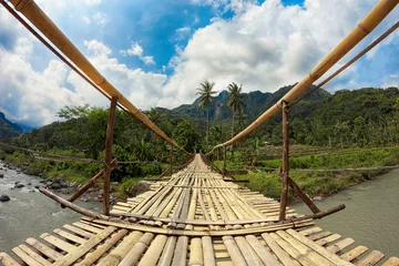 Papier Peint photo autocollant Indonésie Suspension bamboo bridge across the river in a forest and rice f