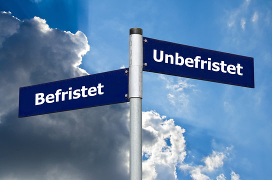 Straßen-Schild vor blauem/bewölktem Himmel welches den Gegensatz zwischen 'Befristet' und 'unbefristet' symbolisiert